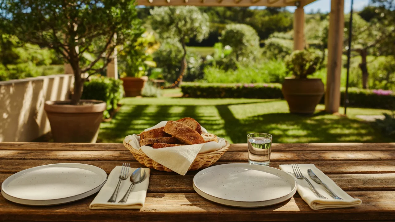 Tavolo da giardino sotto il pergolato con piatti, pane e acqua